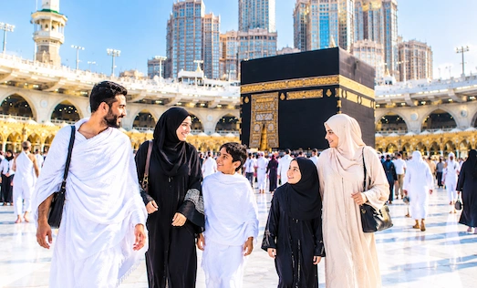 Muslim family and pilgrims walking at Masjid al-Haram in Makkah with the Kaaba in the background